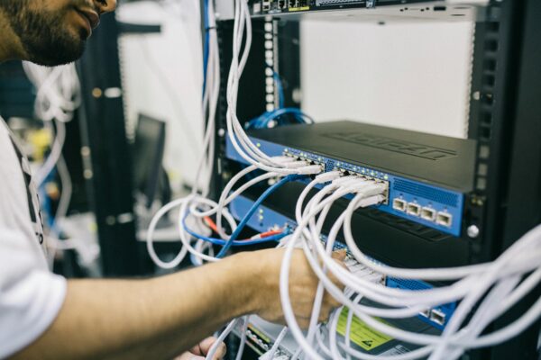 A male IT technician working with a piece of tech with a lot of cables attached. it outsourcing